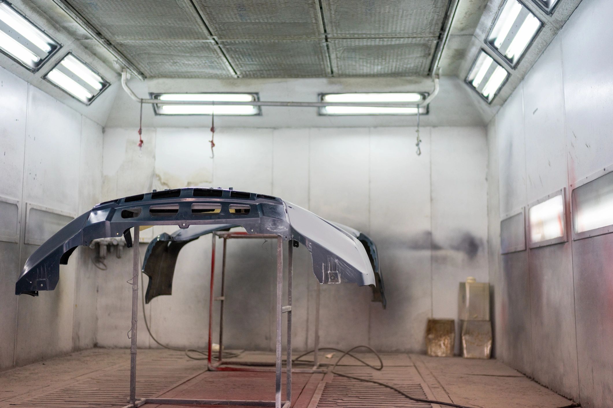 Auto body paint booth with bumper panels ready for refinishing